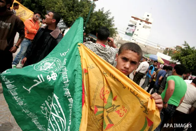 Palestinians wave with Hamas movement and Fatah party flags during a rally celebrating the signing of a reconciliation deal in Gaza city on May 4,2011. Hundreds of Palestinians have gathered to cheer on a unity agreement...