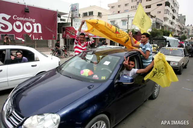 Palestinians wave with Fatah party flags during a rally celebrating the signing of a reconciliation deal in Gaza city on May 4,2011. Hundreds of Palestinians have gathered to cheer on a unity agreement being signed in Ca...