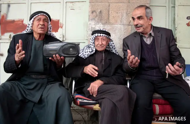 Palestinian men listen to the radio in the West Bank city of Hebron on May 04, 2011 as Palestinians in the West Bank and Gaza Strip gather to celebrate and welcome a reconciliation deal signed by rival movements Hamas an...