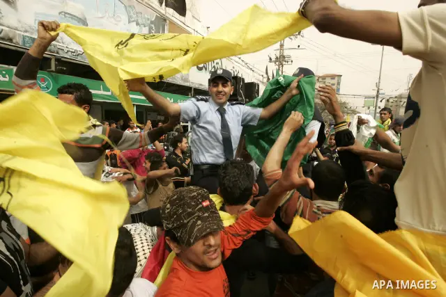 A Palestinian Hamas policeman holds the Fatah flag as he joins celebrations marking the political reconciliation agreement during a rally in Rafah, southern Gaza Strip, on May 4, 2011 as Palestinians in the West Bank and...