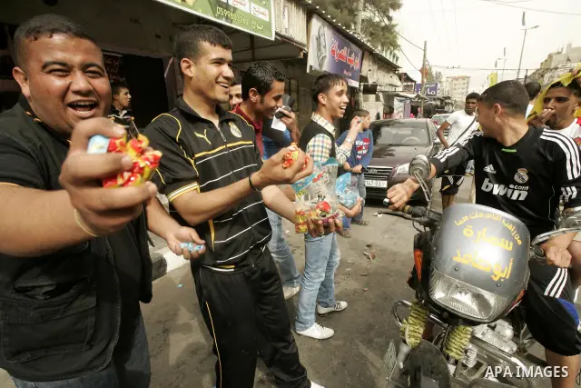 Palestinians distribute sweets during celebrations marking the political reconciliation agreement during a rally in Rafah, southern Gaza Strip, on May 4, 2011 as Palestinians in the West Bank and Gaza Strip gather to wel...