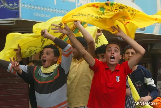 Palestinians wave with Fatah party flags during celebrations marking the political reconciliation agreement during a rally in Rafah, southern Gaza Strip, on May 4, 2011 as Palestinians in the West Bank and Gaza Strip gat...