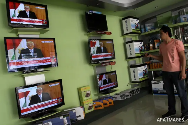 A Palestinian youth watches on TV the signing of the political reconciliation agreement between Fatah and Hamas at his shop in Gaza City on May 04, 201, as Palestinians in the West Bank and Gaza Strip gather to celebrate...