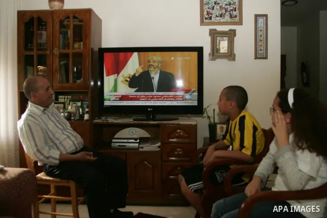 Palestinians watch on TV the signing of the political reconciliation agreement between Fatah and Hamas at their home in Jerusalem's old city on May 04, 201, as Palestinians in the West Bank and Gaza Strip gather to celeb...