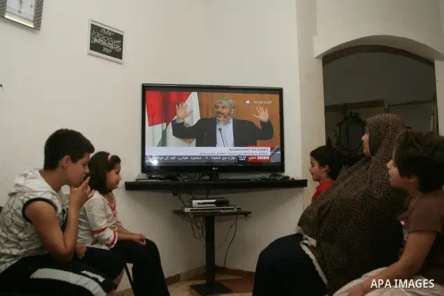 Palestinians watch on TV the signing of the political reconciliation agreement between Fatah and Hamas at their home in Jerusalem's old city on May 04, 201, as Palestinians in the West Bank and Gaza Strip gather to celeb...