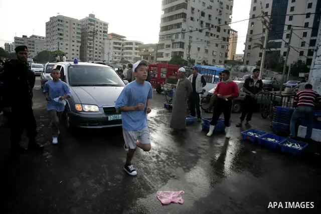 Palestinian schoolboys run past a fish market in Gaza City on May 5, 2011 as they compete in the Gaza Strip's first-ever marathon which runs the entire length of the coastal enclave. Photo by Mohammed Othman