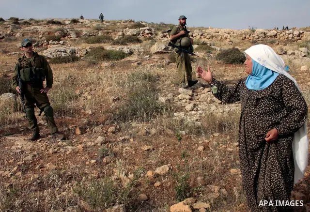 Israeli soldiers stand guard as members of a Palestinian family retrieve items from the rubble of their home after their shacks and tents were destroyed by Israeli bulldozers near the Jewish settlement of Sosia, in the v...