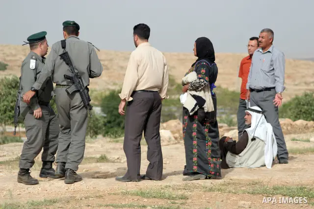 Israeli soldiers stand guard as members of a Palestinian family retrieve items from the rubble of their home after their shacks and tents were destroyed by Israeli bulldozers near the Jewish settlement of Sosia, in the v...