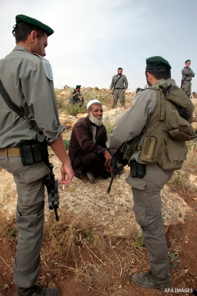 Israeli soldiers stand guard as members of a Palestinian family retrieve items from the rubble of their home after their shacks and tents were destroyed by Israeli bulldozers near the Jewish settlement of Sosia, in the v...