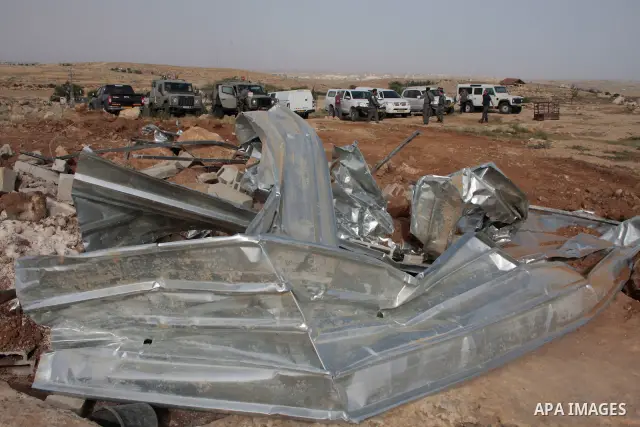Israeli soldiers stand guard as members of a Palestinian family retrieve items from the rubble of their home after their shacks and tents were destroyed by Israeli bulldozers near the Jewish settlement of Sosia, in the v...