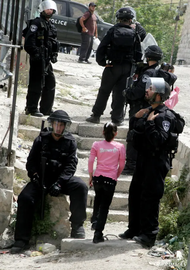 A Palestinian girl walk past Israeli soldiers standing guard during clashes with Palestinian stone-throwers in the flashpoint east Jerusalem neighbourhood of Silwan on May 6,2011. Photo by Mahfouz Abu Turk