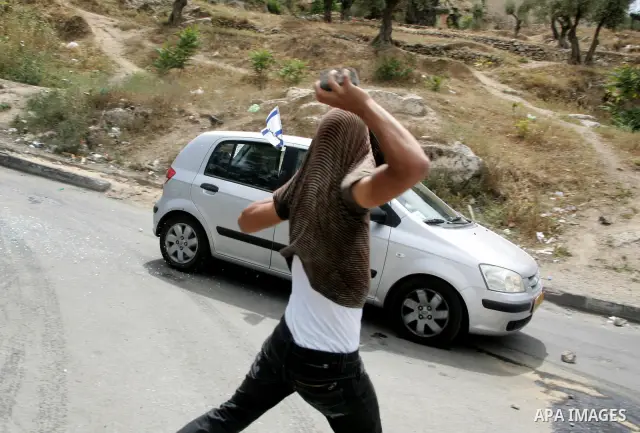 A masked Palestinian youth hurls stones toward a jewish settler car during clashes in the flashpoint east Jerusalem neighbourhood of Silwan on May 6,2011. Photo by Mahfouz Abu Turk
