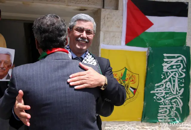 Look alikes of Palestinian Authority President Mahmud Abbas (R) and Hamas leader Khaled Meshaal hug during a rally by supporters of Abbas' Fatah party and Meshaal's Hamas Islamic group on May 6, 2011, in the West Bank vi...