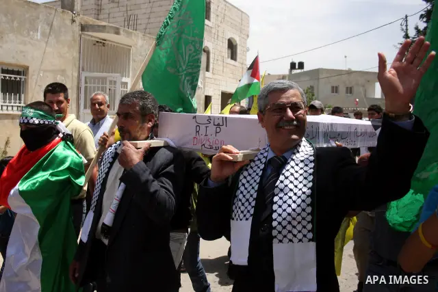 Look alikes of Palestinian Authority President Mahmud Abbas (R) and Hamas leader Khaled Meshaal carry a mock coffin representing the death of the Palestinian political division during a rally by supporters of Abbas' Fata...