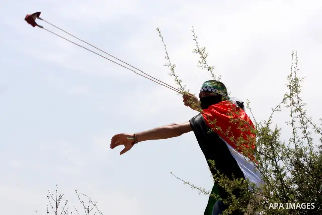 A Palestinian protestor hurls stones toward Israeli forces during a rally on May 6, 2011, in the Israeli-occupied West Bank village of Bilin, to protest against the Israeli occupation and to celebrate the political unity...