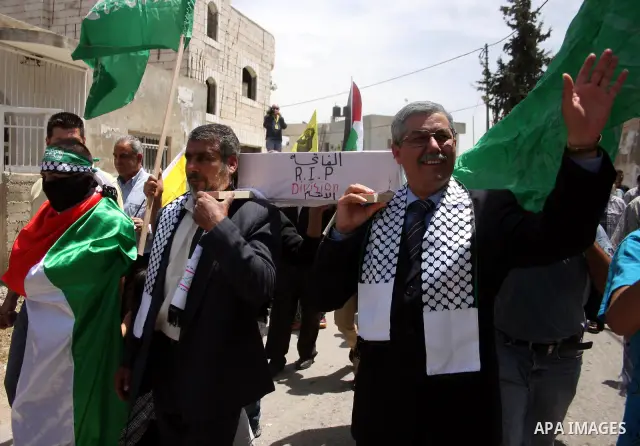 Look alikes of Palestinian Authority President Mahmud Abbas (R) and Hamas leader Khaled Meshaal carry a mock coffin representing the death of the Palestinian political division during a rally by supporters of Abbas' Fata...