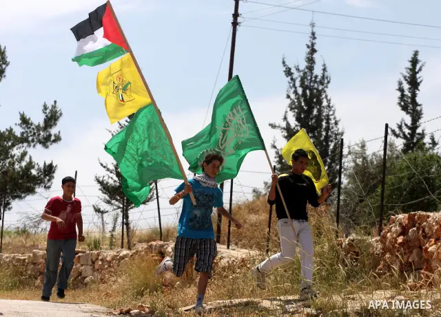 Palestinian protestors carry the Hamas and Fatah flags during a rally on May 6, 2011, in the Israeli-occupied West Bank village of Bilin, to celebrate the political unity reconciliation deal between the Hamas Islamist mo...