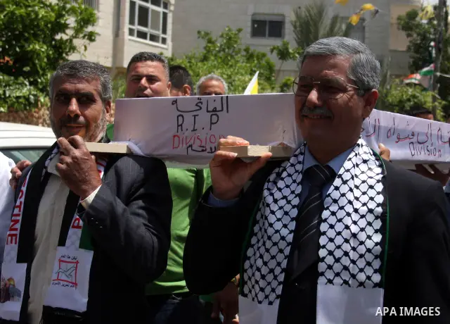 Look alikes of Palestinian Authority President Mahmud Abbas (R) and Hamas leader Khaled Meshaal carry a mock coffin representing the death of the Palestinian political division during a rally by supporters of Abbas' Fata...