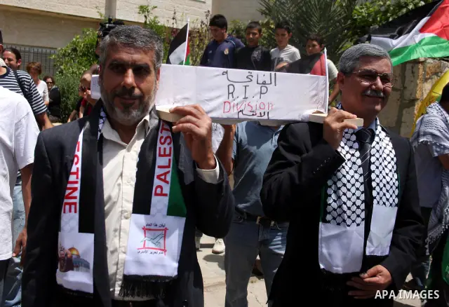 Look alikes of Palestinian Authority President Mahmud Abbas (R) and Hamas leader Khaled Meshaal carry a mock coffin representing the death of the Palestinian political division during a rally by supporters of Abbas' Fata...