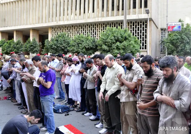 Egyptian military police stand guard as a boy holding the national flag stands before men performing their afternoon prayers during a protest outside the U.S. embassy in Cairo, Egypt, Friday, May 6, 2011, to denounce the...