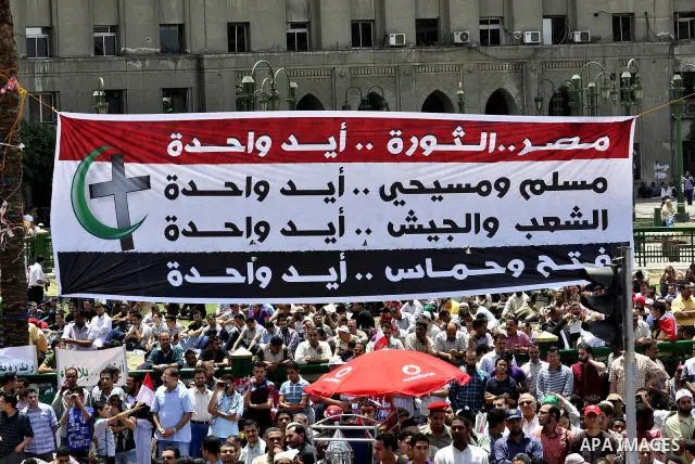 Egyptian demonstrators hold signs during a rally at Cairo's Tahrir Square on May 13, 2011 during a protest calling for national unity after attacks on Egyptian churches, and solidarity with the Palestinians as they mark...
