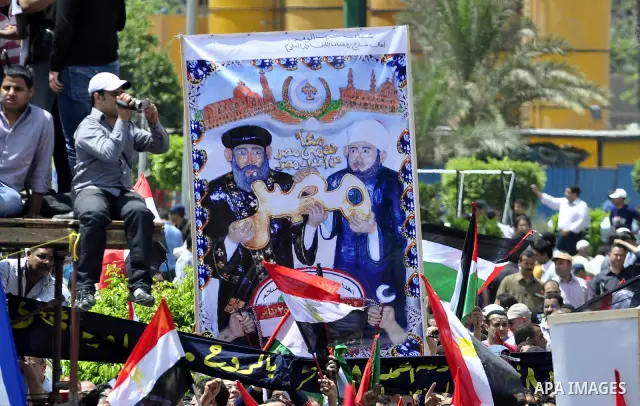 Egyptian demonstrators hold signs during a rally at Cairo's Tahrir Square on May 13, 2011 during a protest calling for national unity after attacks on Egyptian churches, and solidarity with the Palestinians as they mark...
