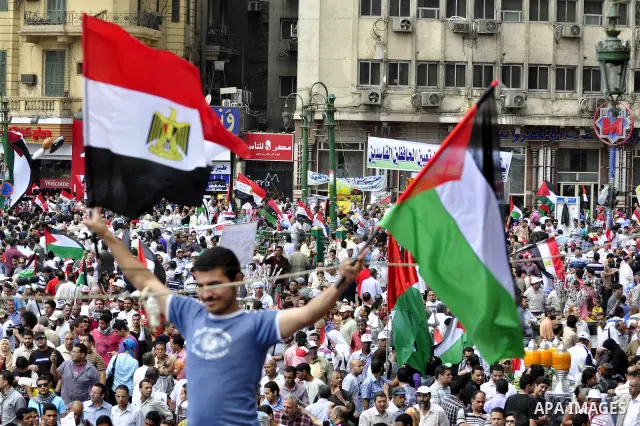 Egyptian demonstrators wave Palestinian flags and Egyptian flags during a rally at Cairo's Tahrir Square on May 13, 2011 during a protest calling for national unity after attacks on Egyptian churches, and solidarity with...