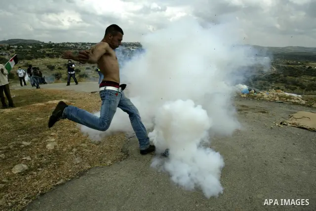 A Palestinian protester kicks back a tear gas canister towards Israeli troops during a protest against Israel's controversial separation barrier and to mark the 63th anniversary of "Nakba" (catastrophe) on May 13, 2011in...