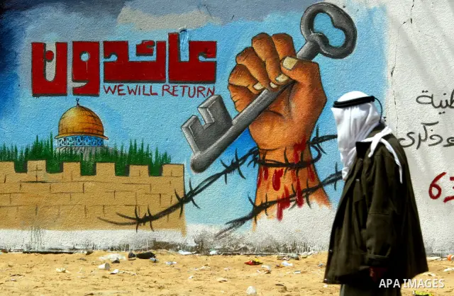 A Palestinian man poses in front of a mural painting on the theme of return of refugees to their land in what is now Israel on May 14, 2011 in the southern Gaza Strip refugee camp of Rafah, where Palestinians are marking...