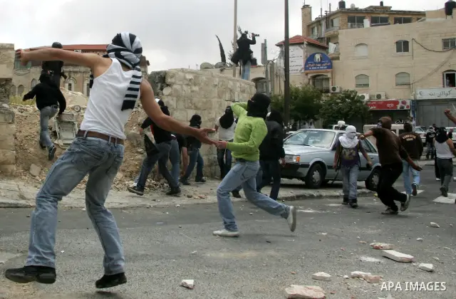 Palestinian youths throw stones during clashes following the funeral of a teenager who died after being shot as Palestinians launched events to mourn the 1948 creation of the Jewish state in Jerusalem the day before, aft...