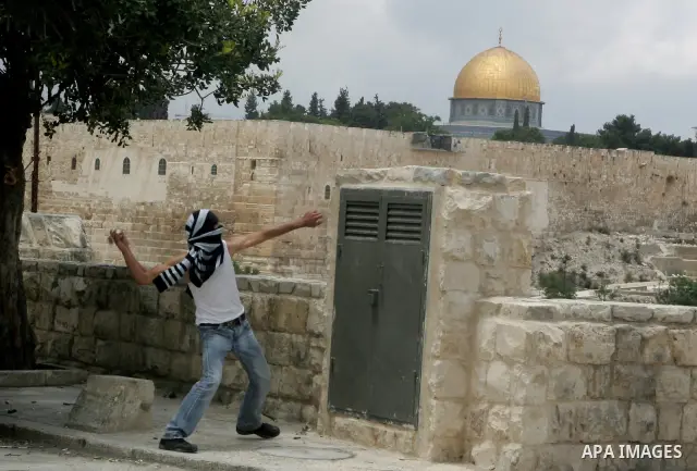 A Palestinian throws a rock during clashes following the funeral of a teenager who died after being shot as Palestinians launched events to mourn the 1948 creation of the Jewish state in Jerusalem the day before, after h...