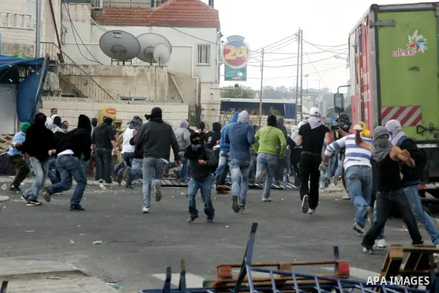 Palestinian youths throw stones during clashes following the funeral of a teenager who died after being shot as Palestinians launched events to mourn the 1948 creation of the Jewish state in Jerusalem the day before, aft...