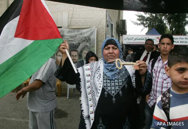 Palestinians hold national flag during clashes following the funeral of a teenager who died after being shot as Palestinians launched events to mourn the 1948 creation of the Jewish state in Jerusalem the day before, aft...