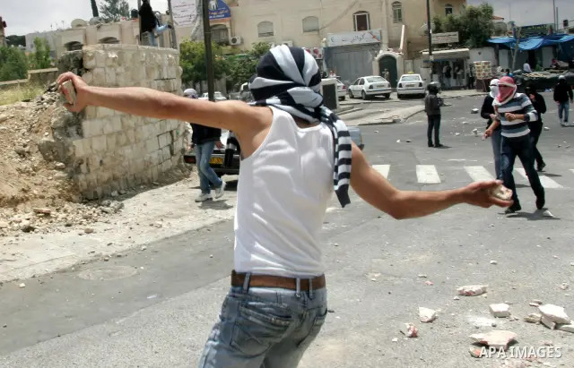 Palestinian youths throw stones during clashes following the funeral of a teenager who died after being shot as Palestinians launched events to mourn the 1948 creation of the Jewish state in Jerusalem the day before, aft...