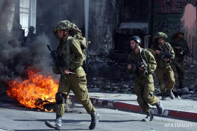 Israeli soldiers run past burning tires during clashes with Palestinian stone throwers at the Israeli manned Qalandia checkpoint between Jerusalem and the West Bank city if Ramallah on May 14, 2011, as Palestinians gathe...