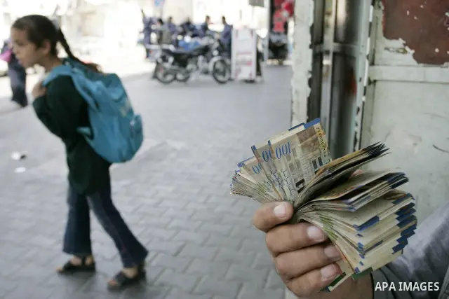 A Palestinian man displays the Israeli shekels at a black markets in the southern Gaza Strip town of Rafah on May 14, 2011. Photo by Abed Rahim Khatib