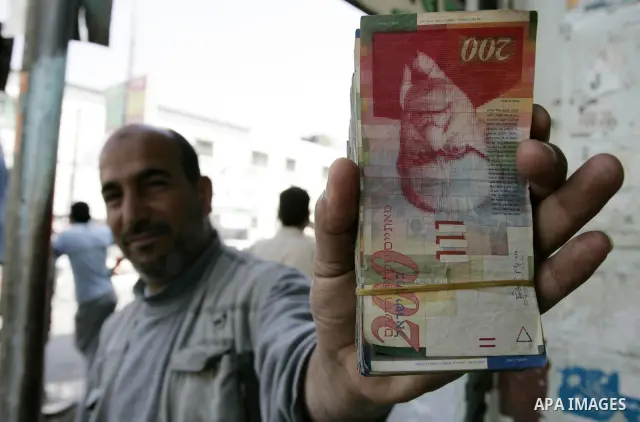 A Palestinian man displays the Israeli shekels at a black markets in the southern Gaza Strip town of Rafah on May 14, 2011. Photo by Abed Rahim Khatib