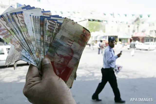 A Palestinian man displays the Israeli shekels at a black markets in the southern Gaza Strip town of Rafah on May 14, 2011. Photo by Abed Rahim Khatib