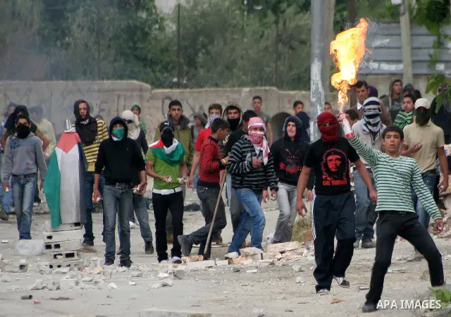 Palestinian youths throw stones at Israeli soldiers during confrontations in the West Bank city of Hebron, while Palestinians mourned on May 15, 2011 the "nakbah" anniversary of Israel's creation in 1948, as a result of...