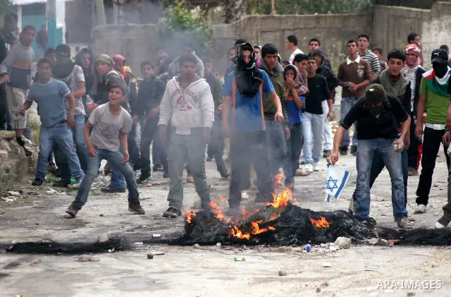 Palestinian youths throw stones at Israeli soldiers during confrontations in the West Bank city of Hebron, while Palestinians mourned on May 15, 2011 the "nakbah" anniversary of Israel's creation in 1948, as a result of...