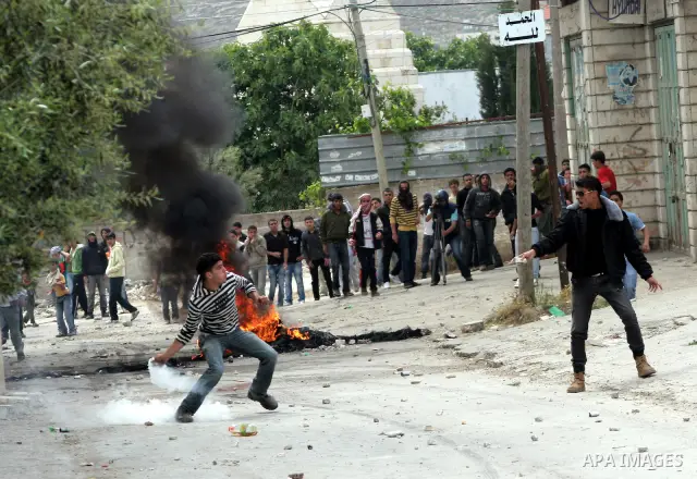 Palestinian youths throw stones at Israeli soldiers during confrontations in the West Bank city of Hebron, while Palestinians mourned on May 15, 2011 the "nakbah" anniversary of Israel's creation in 1948, as a result of...