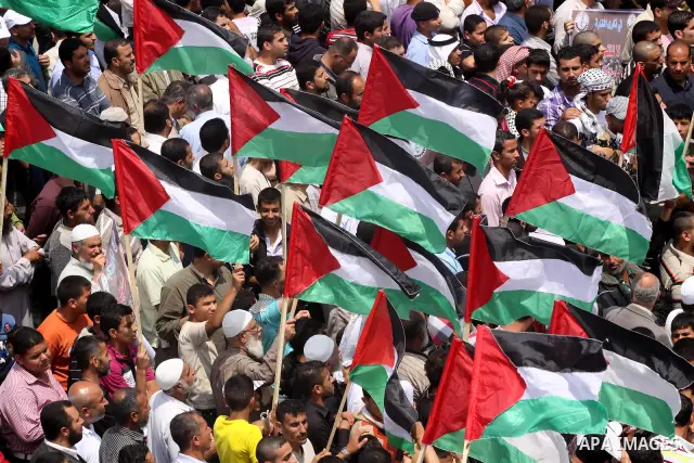 Palestinian protesters wave Palestinian national flags during a demonstration in front of the Erez border crossing in the northern Gaza Strip, on May 15, 2011, as people gathered to mark the "nakbah" or "catastrophe" ann...