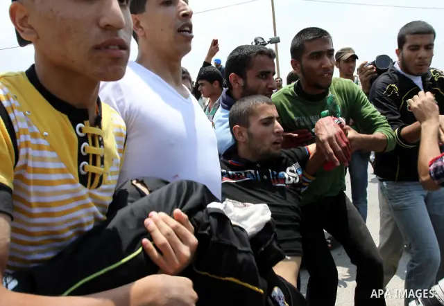 Palestinians carry a wounded protester after Israeli troops opened fire during a massive march heading towards the Erez border crossing in the northern Gaza Strip, on May 15, 2011, as people gathered to mark the "nakbah"...