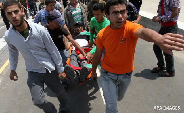 Palestinians carry a wounded protester after Israeli troops opened fire during a massive march heading towards the Erez border crossing in the northern Gaza Strip, on May 15, 2011, as people gathered to mark the "nakbah"...