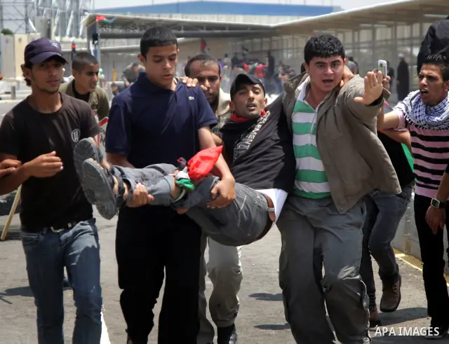 Palestinians carry a wounded protester after Israeli troops opened fire during a massive march heading towards the Erez border crossing in the northern Gaza Strip, on May 15, 2011, as people gathered to mark the "nakbah"...