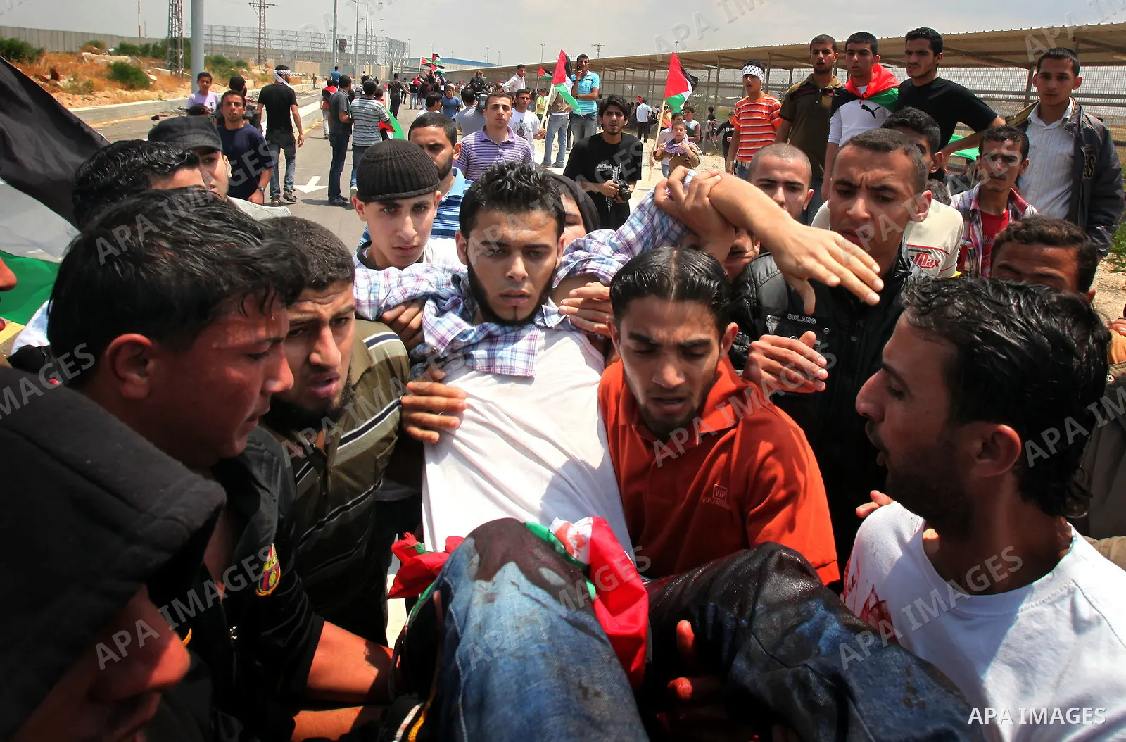 Palestinians carry a wounded protester after Israeli troops opened fire during a massive march heading towards the Erez border crossing in the northern Gaza Strip, on May 15, 2011, as people gathered to mark the "nakbah"...