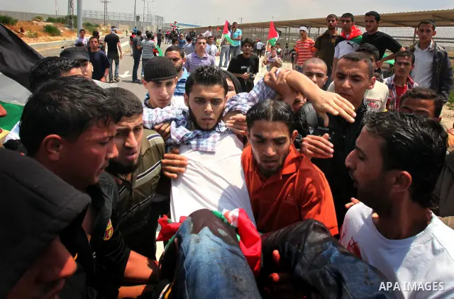 Palestinians carry a wounded protester after Israeli troops opened fire during a massive march heading towards the Erez border crossing in the northern Gaza Strip, on May 15, 2011, as people gathered to mark the "nakbah"...