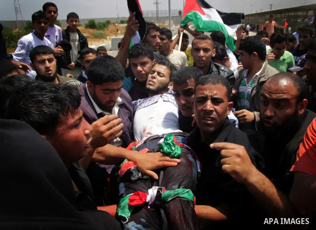 Palestinians carry a wounded protester after Israeli troops opened fire during a massive march heading towards the Erez border crossing in the northern Gaza Strip, on May 15, 2011, as people gathered to mark the "nakbah"...