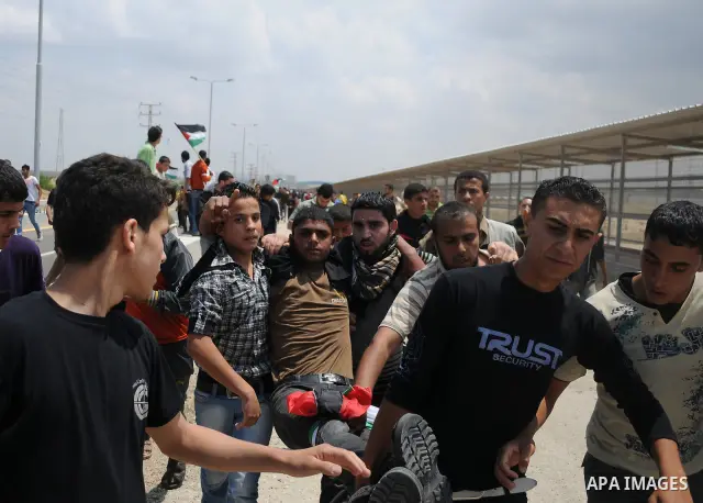 Palestinians carry a wounded protester after Israeli troops opened fire during a massive march heading towards the Erez border crossing in the northern Gaza Strip, on May 15, 2011, as people gathered to mark the "nakbah"...