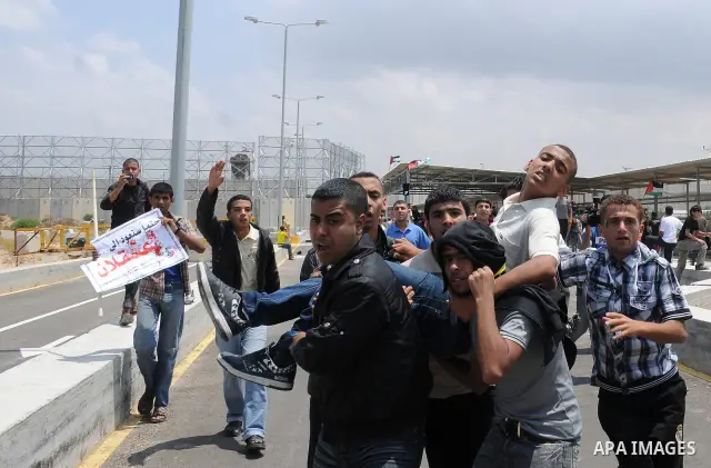 Palestinians carry a wounded protester after Israeli troops opened fire during a massive march heading towards the Erez border crossing in the northern Gaza Strip, on May 15, 2011, as people gathered to mark the "nakbah"...